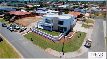 Modern white two-story house with landscaped lawn at a street corner.
