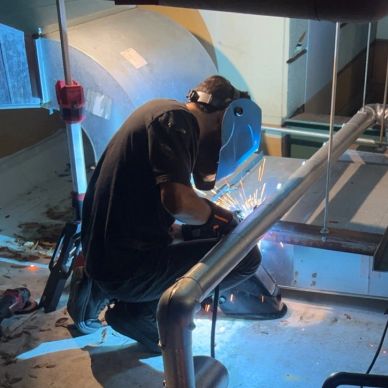 Welding work being performed in an industrial setting with sparks flying.