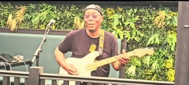 Musician playing electric guitar on stage.