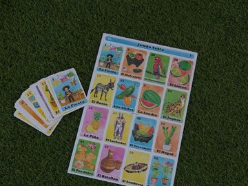 Traditional Mexican Lotería game cards laid out on grass.