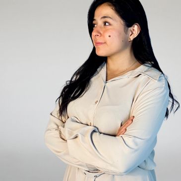 Mujer con expresión pensativa y brazos cruzados.