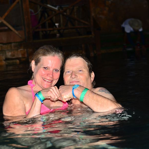 Couple in water making a fist heart shape.