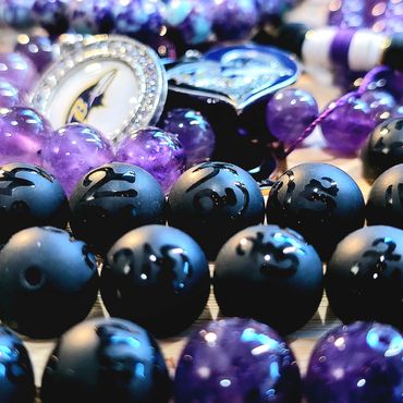 Close-up of purple and black beaded jewelry with heart-shaped pendants.