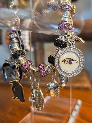Close-up of a charm bracelet with Baltimore Ravens logo and football-themed charms.