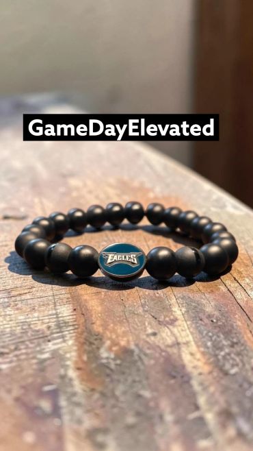 Black beaded bracelet with Eagles emblem on a wooden surface.
