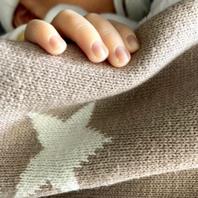 Close-up of a baby's hand holding a blanket while sleeping.