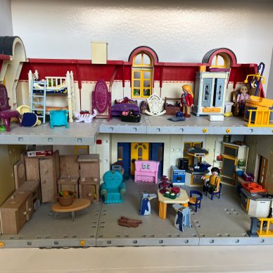 A detailed dollhouse with multiple rooms and miniature furniture.