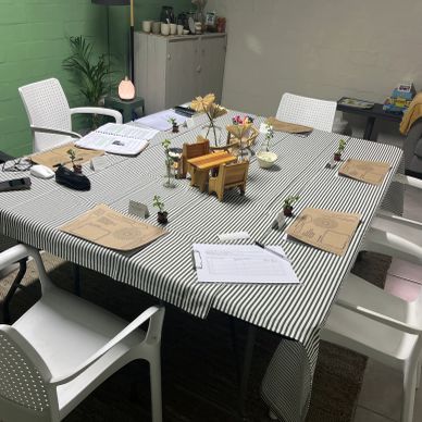 Dining table set for a meal with striped tablecloth and white chairs.