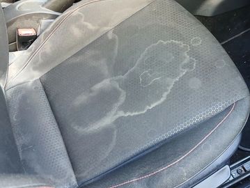 Stained car seat upholstery with clear water marks.
