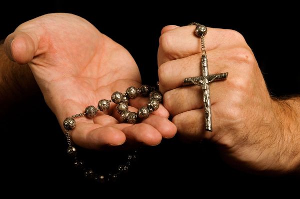 Man clutches a rosary in his hands