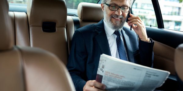 A businessman sitting in the back seat of a car while working on paperwork