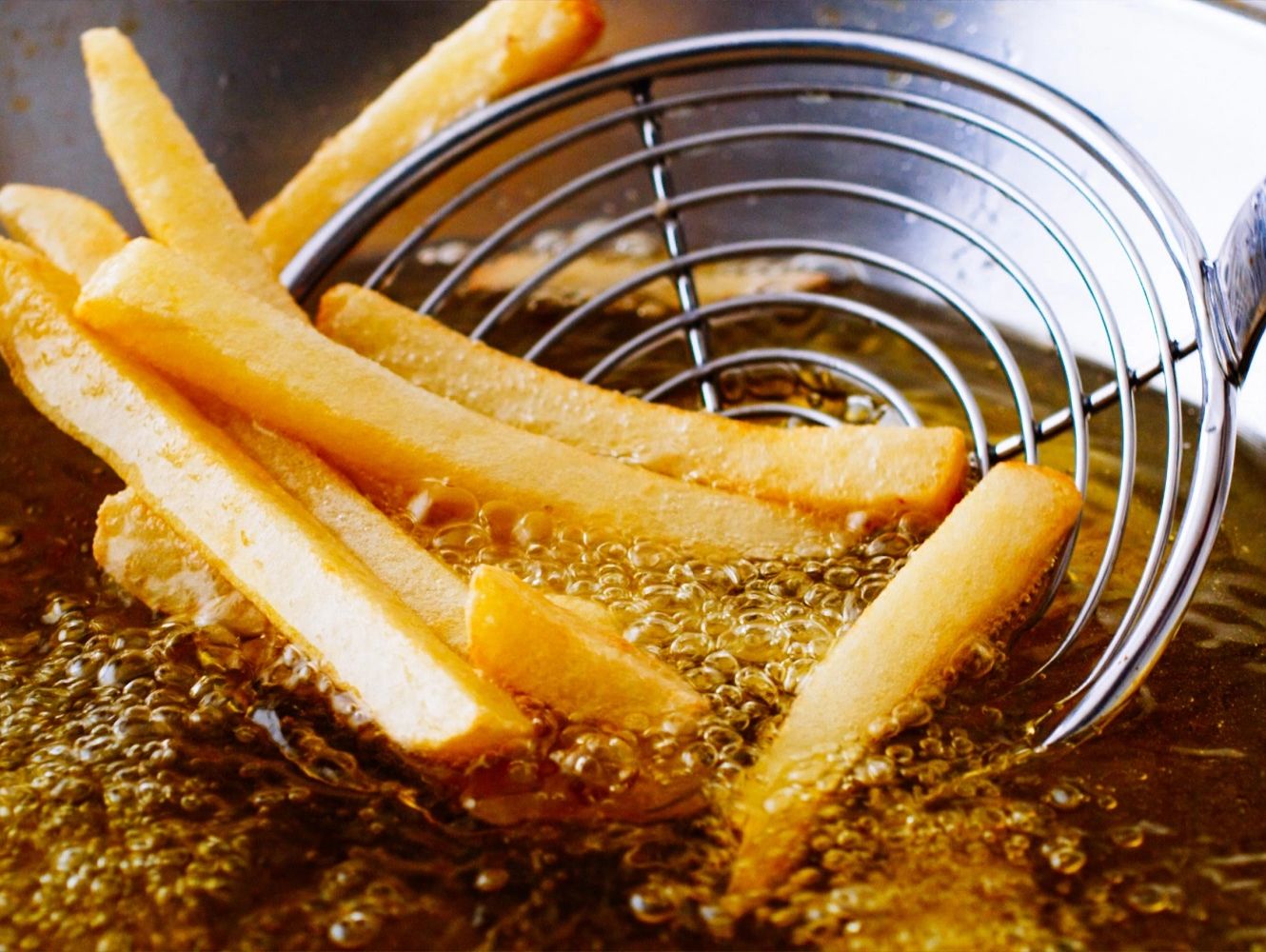 French fries being taken out of a deep fryer