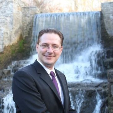 Kyle Edwards, the owner of Affix Label and Print Inc., in front of a waterfall at the Cambridge Mill.