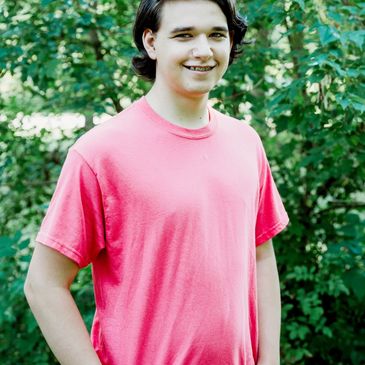 Braedyn Edwards from the Affix Label and Print Inc. shipping department, in front of greenery.