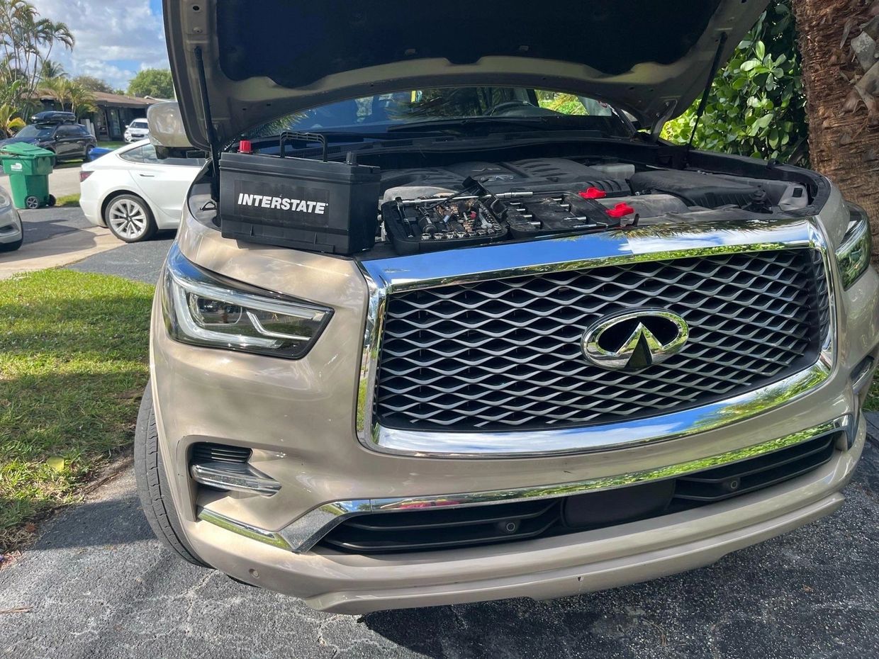 Silver Infiniti SUV with open hood and Interstate battery on front.