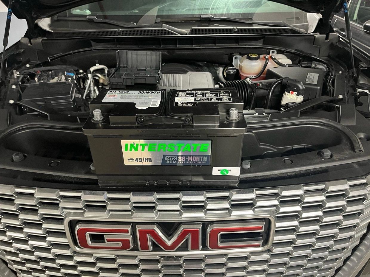Car engine bay with an Interstate battery installed in a GMC vehicle.