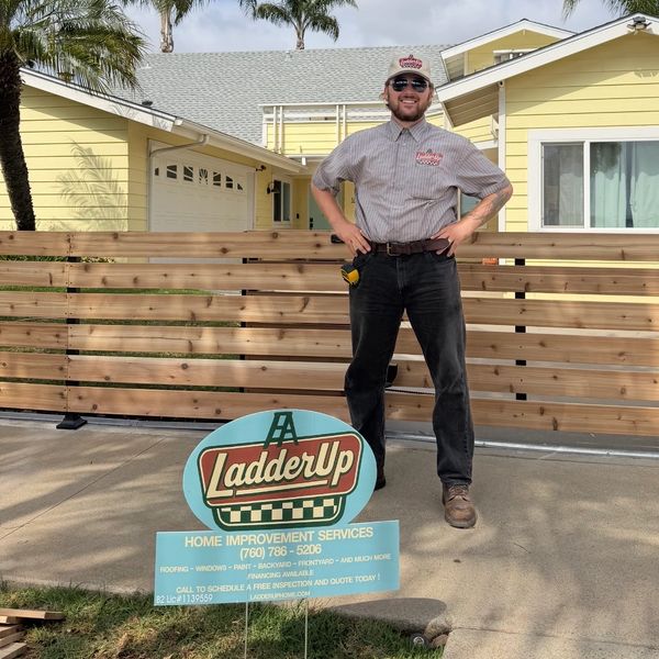 Man standing confidently in front of a house with a LadderUp sign.