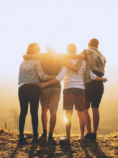 A group of four people, two adults and two children watching the sunset, holding each other.