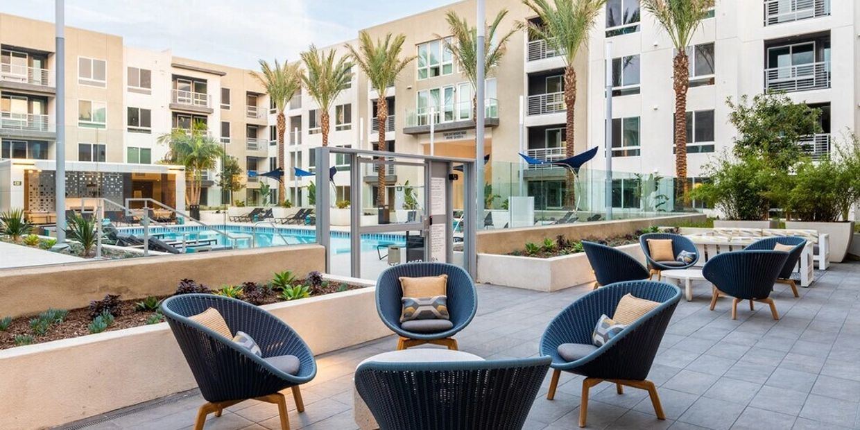 Modern outdoor seating area near a pool in an apartment complex.