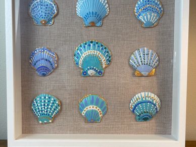 Nine decorative blue seashells in a wooden frame.