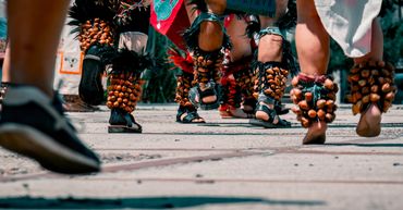 Close-up of dancers' feet adorned with traditional ankle rattles during a cultural dance.
