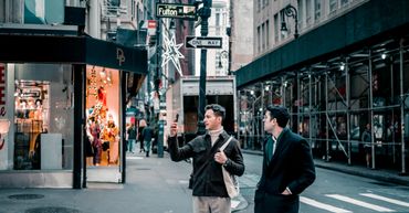Two men walking and talking on a city street near Fulton St.