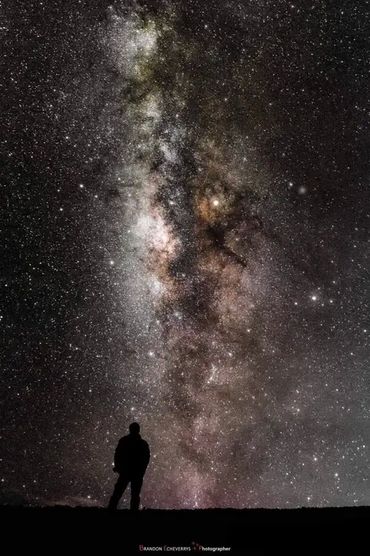 Silhouette of a person gazing at the vibrant Milky Way in the night sky.