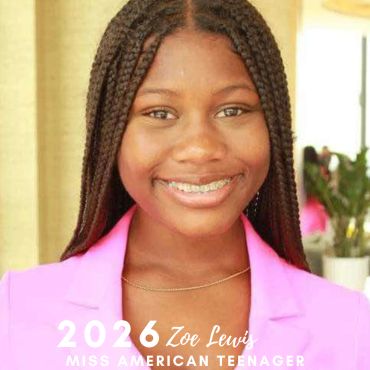 A smiling young girl with braided hair wearing a pink blazer.