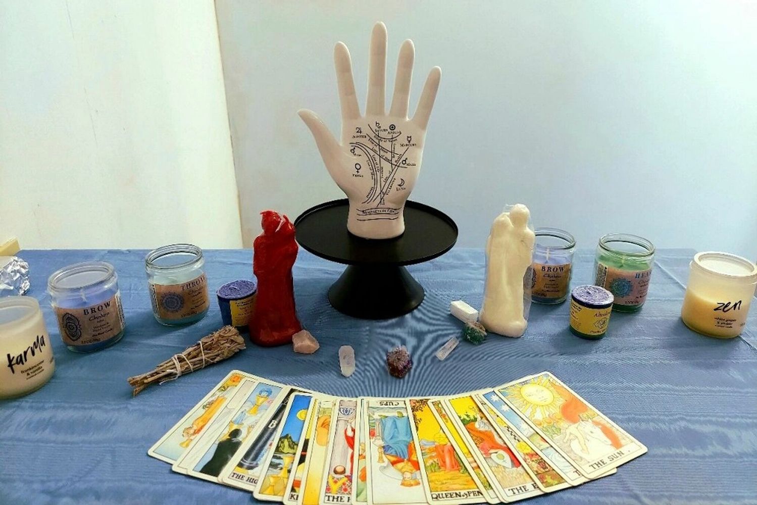 Psychic Ashley's table with a 3D palm reading model, tarot cards, candles, crystals, sage.