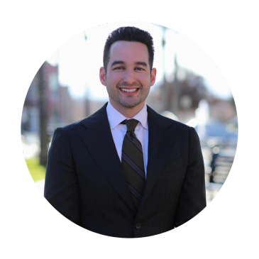 Man in suit smiling outdoors.