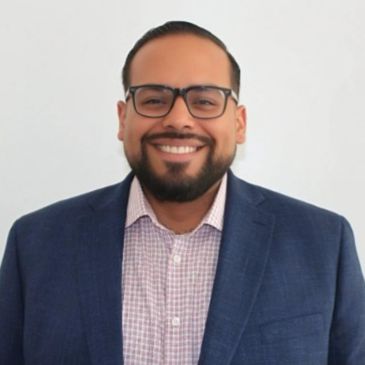 Smiling man wearing glasses and a suit jacket.
