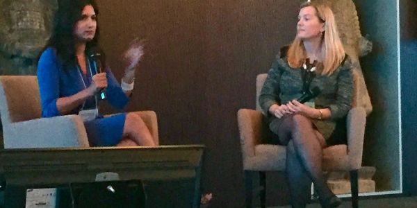 Two women engaged in a discussion during a formal event.