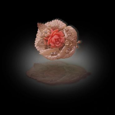 Intricately carved flower brooch with a central red rose.