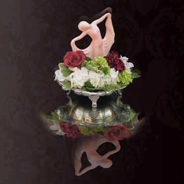 Elegant ballet couple figurine with flowers and reflection.
