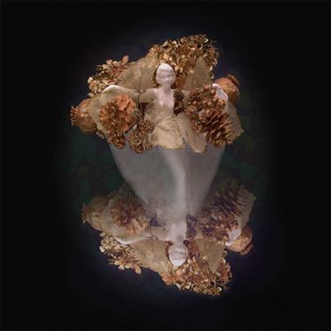 Surreal doll with pinecones and floral decorations.