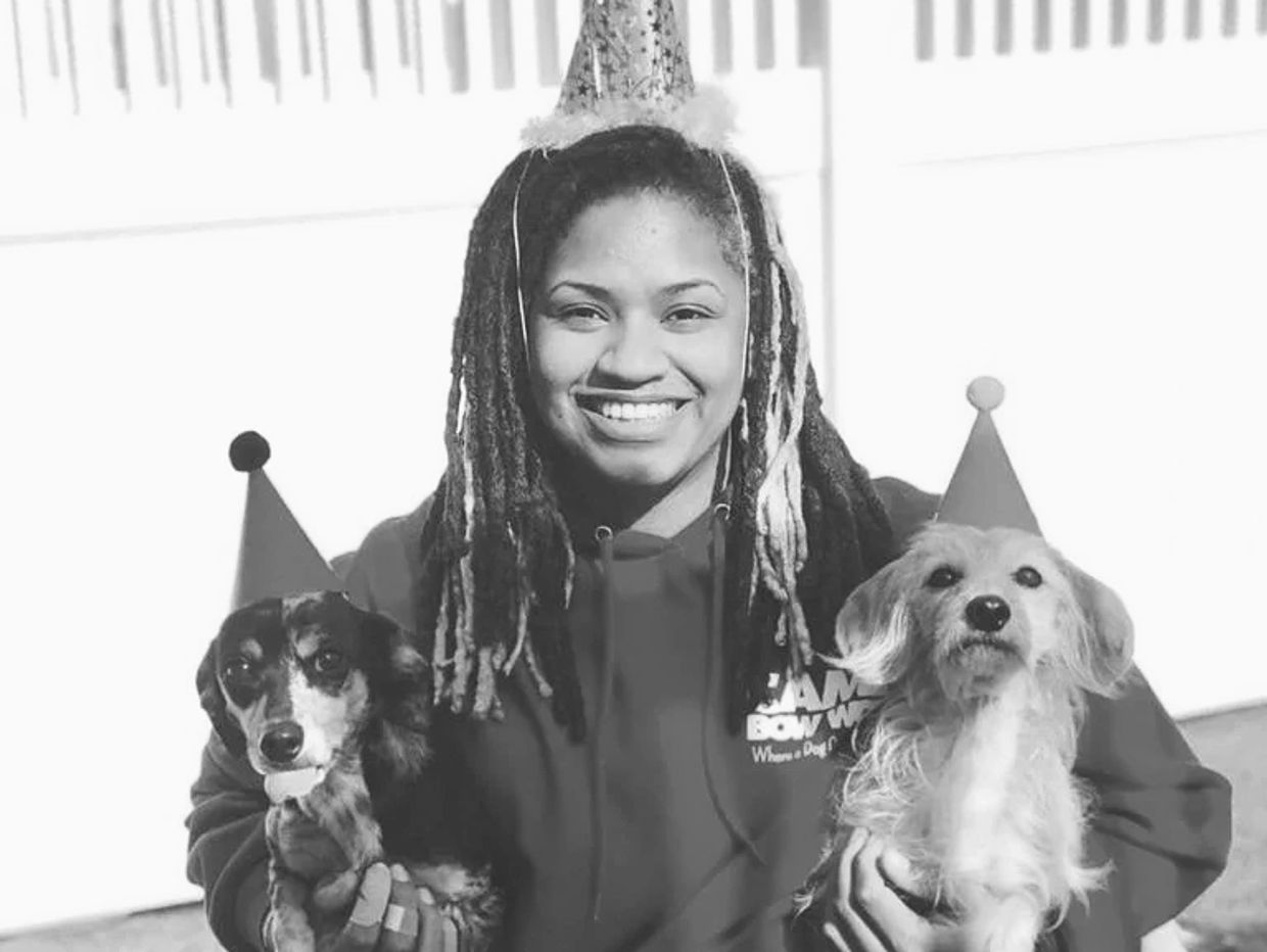 black girl with locs in red hoodie holding two dachshunds dogs wearing hats