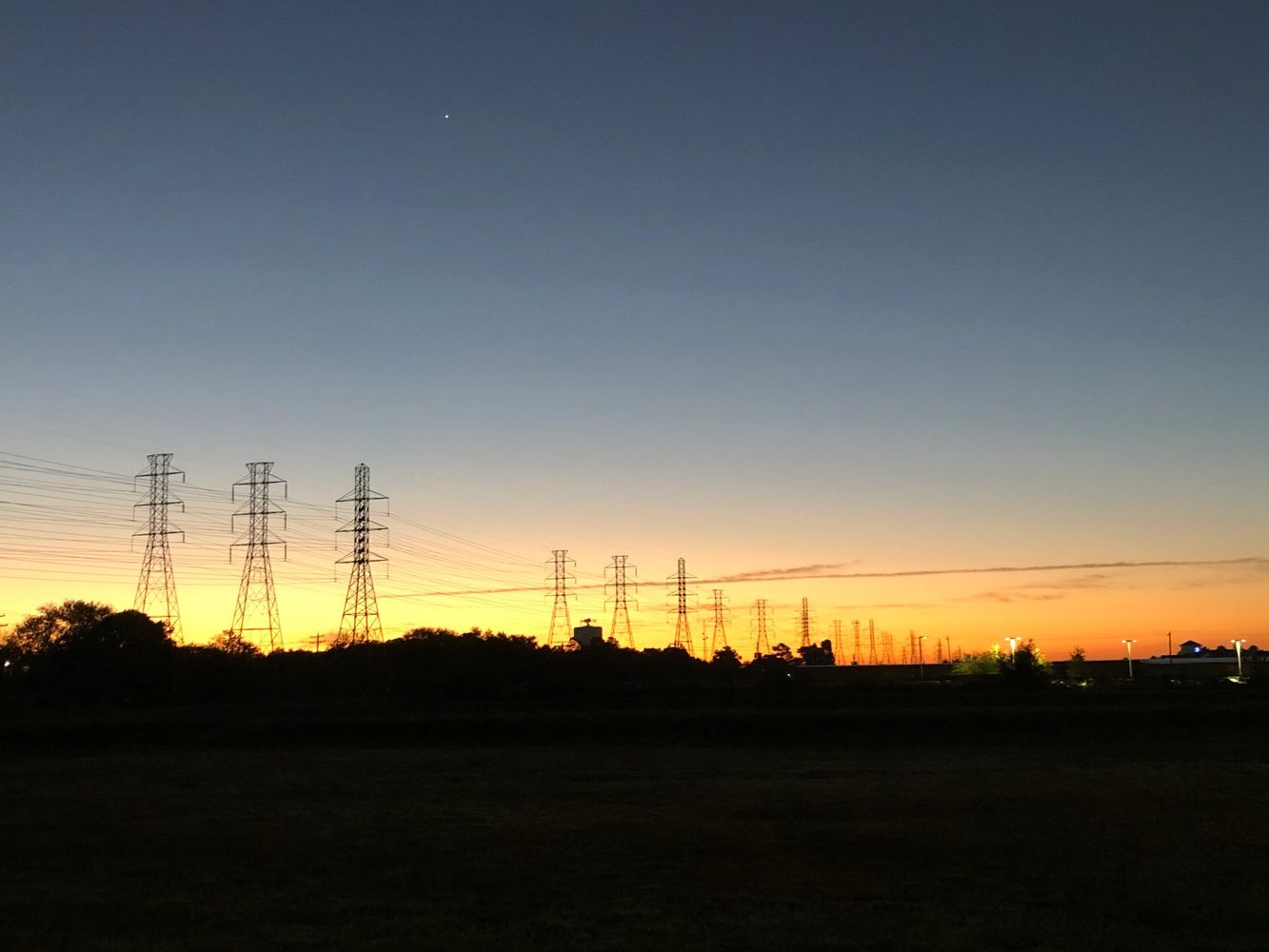 Sunrise over an infinite row of high power lines. Venus hovers overhead.
