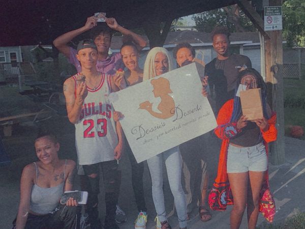 Group of friends holding a sign outdoors.