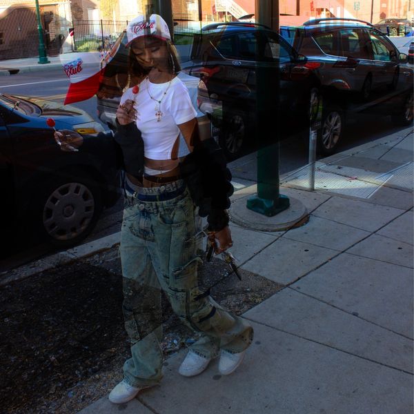 Double exposure of a woman holding a lollipop on a city sidewalk.