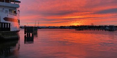 Sunset over a harbor with vibrant orange and red reflections on the water.