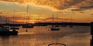 Sailboats anchored on calm water during a golden sunset.