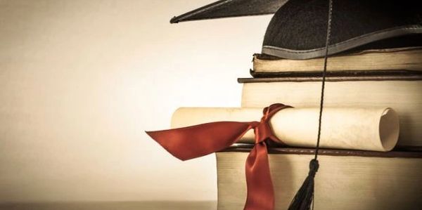 Graduation cap and diploma resting on a stack of books.