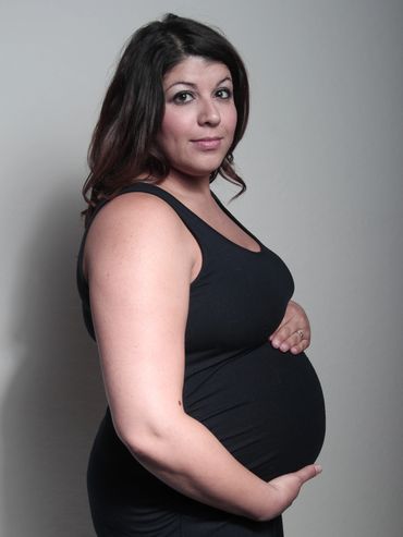 Pregnant woman in a black dress posing.