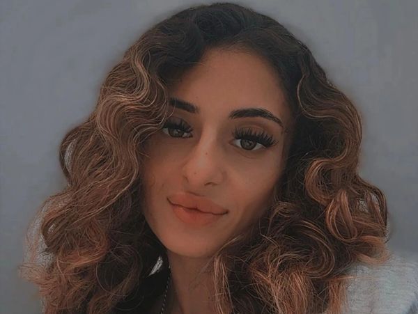 Close-up of a woman with curly hair and subtle makeup.