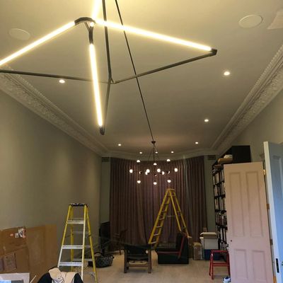 Modern star-shaped ceiling light in a room under renovation with ladders and furniture.