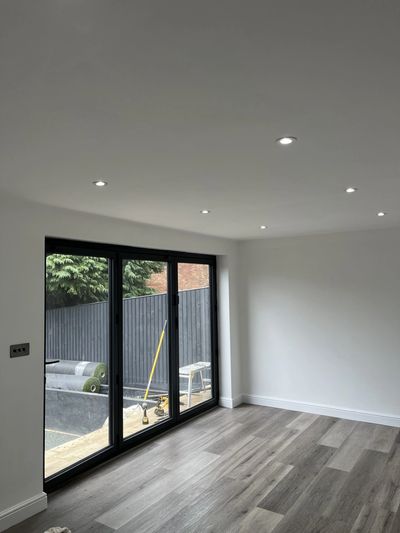 Empty modern room with wood flooring and large sliding glass doors.