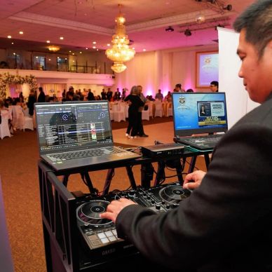 DJ performing at an indoor event with dancing guests.