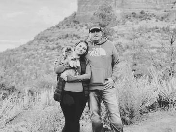 Couple with dog posing outdoors in nature.