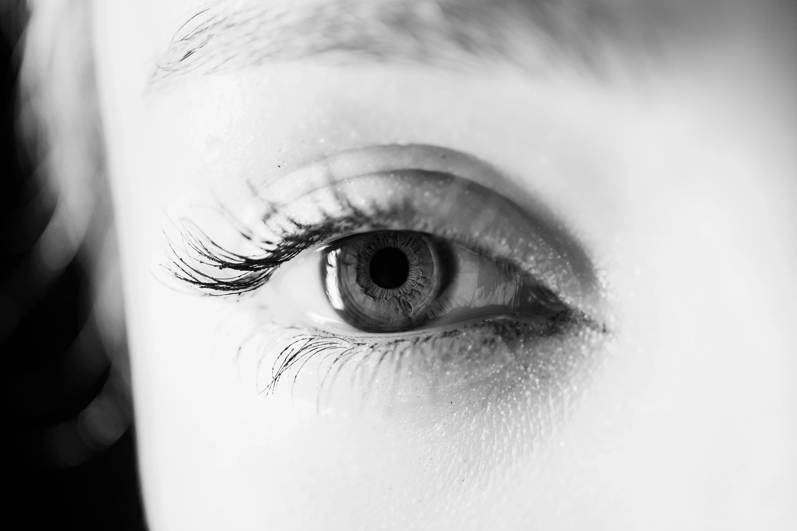 Close-up black and white photo of a human eye with detailed eyelashes.
