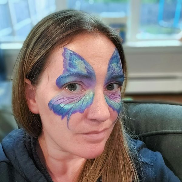 Girl with blue and purple butterfly wings painted on her face. Long Island facepainter